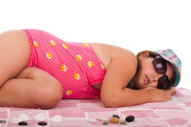 Girl in swimsuit sleeping at the beach clipart