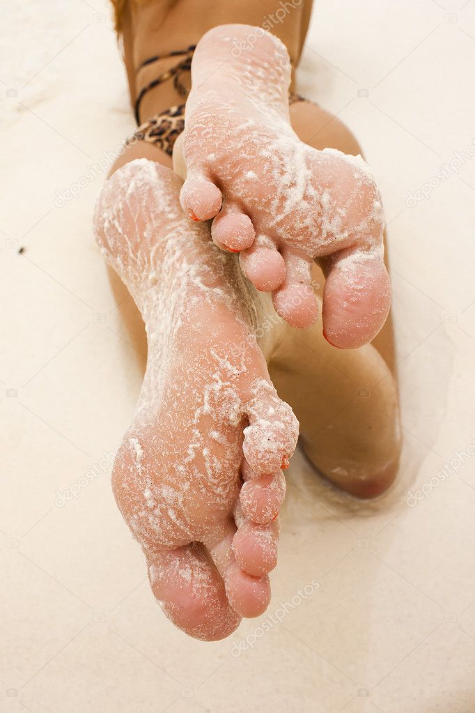 Part of body of a young woman - grain of white sand on foot
