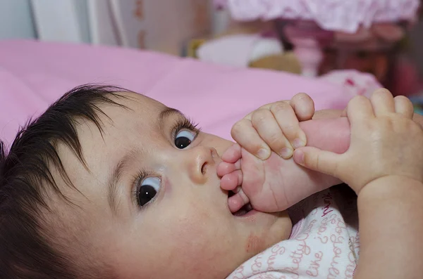 Bebé chica chupando su dedo del pie — Foto de Stock