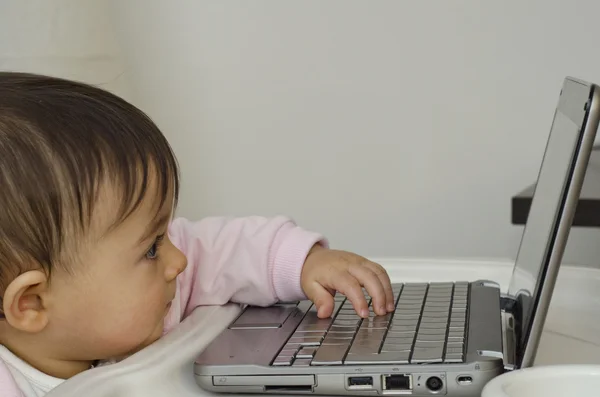 1 έτος κοριτσάκι προσπαθεί να χρησιμοποιήσει το netbook — Φωτογραφία Αρχείου