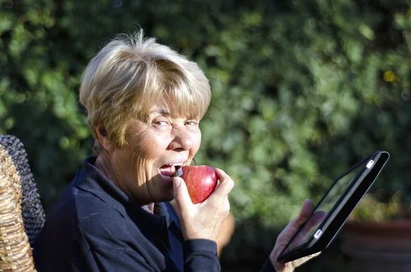 Пенсионерка расслабляется на открытом воздухе со своим смартфоном — стоковое фото