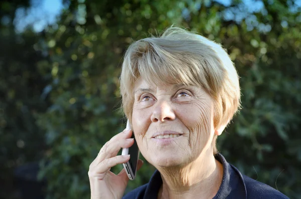 Starszy kobieta mówi na zewnątrz telefonu — Zdjęcie stockowe