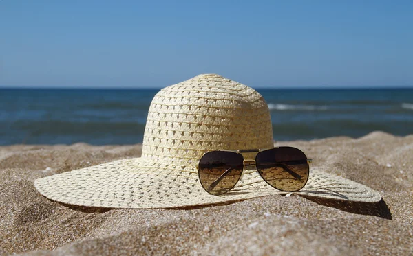 Paglia e occhiali da sole sulla spiaggia — Foto Stock