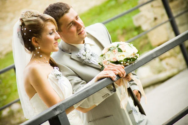 Onlangs getrouwd Kaukasische paar staande knuffelen op de brug — Stockfoto