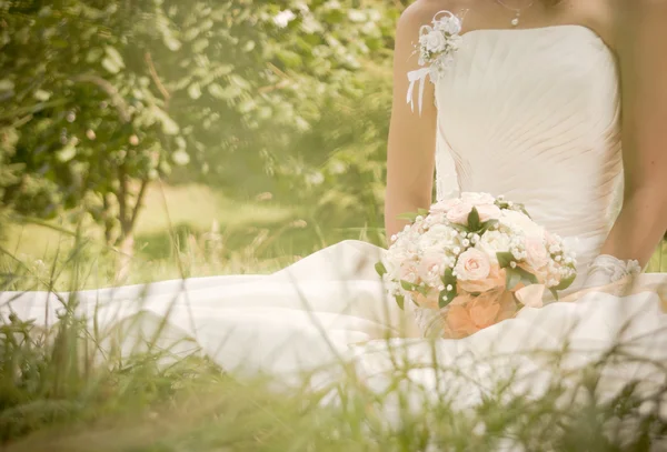 Fiatal gyönyörű menyasszony az esküvői csokrot a füvön — Stock Fotó