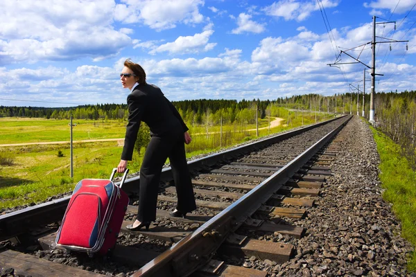 Uma mulher com uma mala na estrada de ferro . — Fotografia de Stock