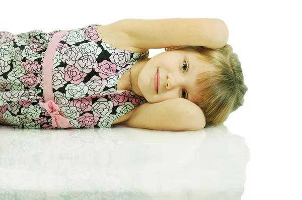 Een mooi klein meisje op de vloer liggen. geïsoleerd op het whit — Stockfoto