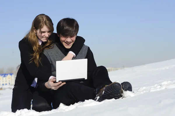 Netbook ile kar üzerinde oturan iki genç — Stok fotoğraf
