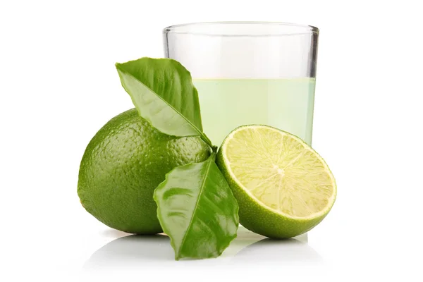 Glass of lime juice and lime fruits with green leaves isolated — Stock Photo, Image