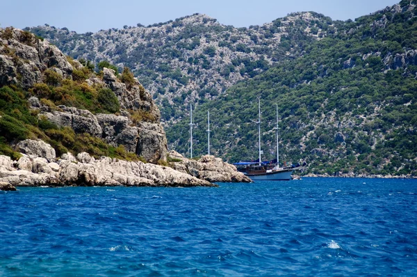 Stock image The yacht in harbor among rocks and blue sea