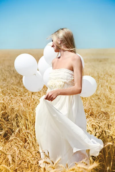 Beautiful girl with white balloons in the field — Stock Photo, Image