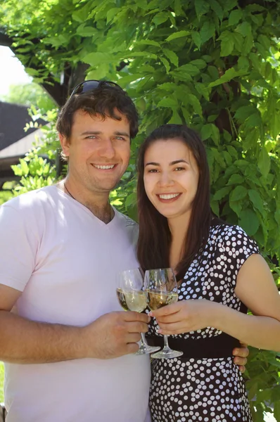 Casal segurando copos de vinho branco fazendo um brinde — Fotografia de Stock
