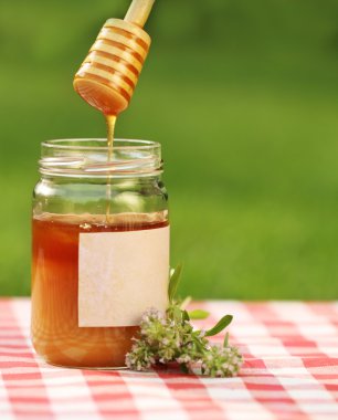 Jar of honey against nature background clipart