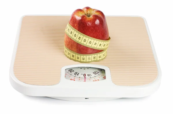 Масштаб, лента и яблоко на белом — стоковое фото