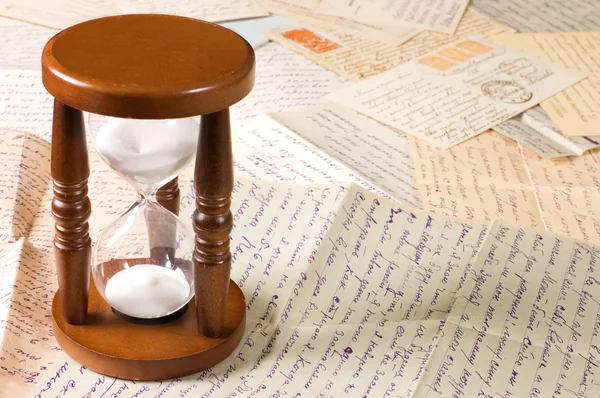 Песочные часы на старых письмах — стоковое фото