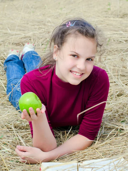 Το κορίτσι με ένα μήλο σε ένα ξηρό χόρτο — Φωτογραφία Αρχείου