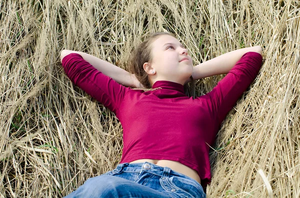 Chica se acuesta en una hierba seca — Foto de Stock