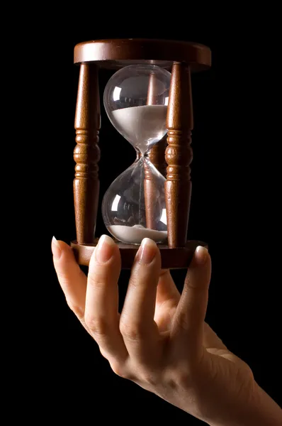 Пісочний годинник в руках на чорному — стокове фото