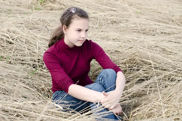 Menina Senta-se em uma grama seca — Fotografia de Stock