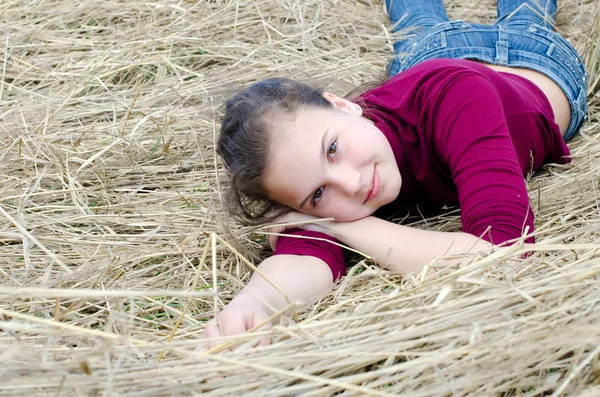 Menina coloca em uma grama seca — Fotografia de Stock