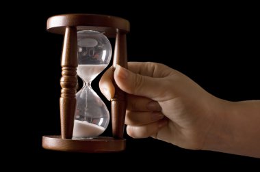 Hourglass in hands on a black clipart