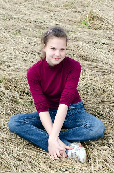 Menina Senta-se em uma grama seca — Fotografia de Stock