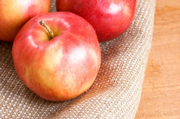 Äpplen på en säckväv på ett träbord — Stockfoto