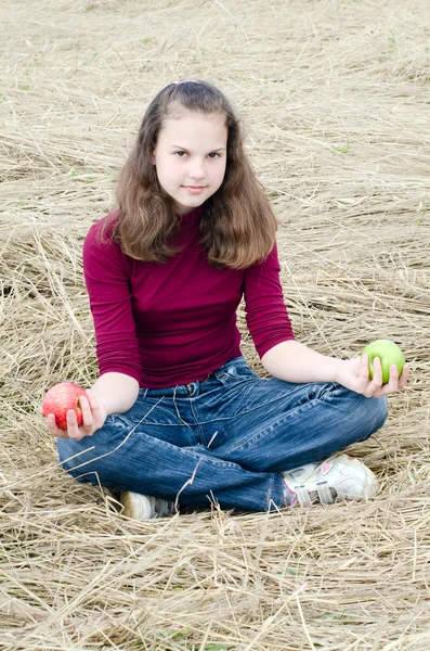 The girl with an apple on a dry grass — Stock Photo, Image