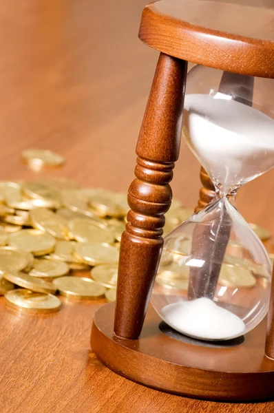 Часы и монеты на деревянном столе — стоковое фото
