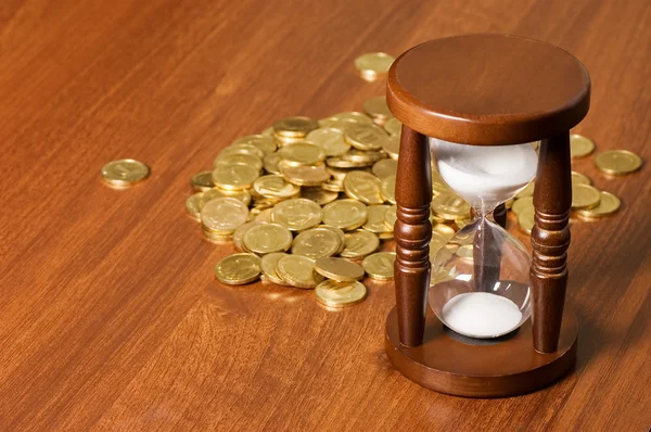 Ampulhetas e moeda Em mesa de madeira — Fotografia de Stock