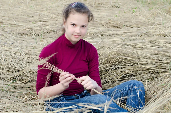 Dívka sedí na suché trávy — Stock fotografie
