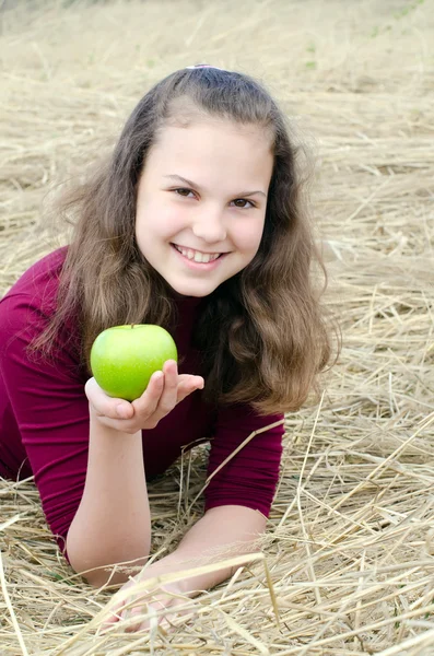 Het meisje met een appel op een droog gras — Stockfoto