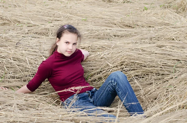 Menina coloca em uma grama seca — Fotografia de Stock
