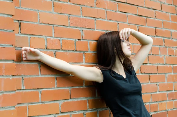 Молода сумна дівчина на цегляних стінах — стокове фото
