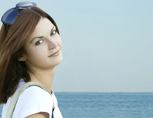 Fiatal nő pózol a tenger partján napszemüveget visel — Stock Fotó