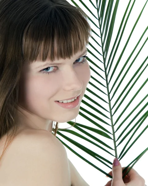 Красивое лицо женщины, прячущейся за большим зеленым пальмовым листом — стоковое фото