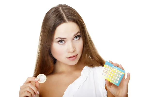Mooi meisje met condoom en contraceptieve pillen. — Stockfoto