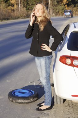 Young woman standing by her damaged car and calling for help clipart