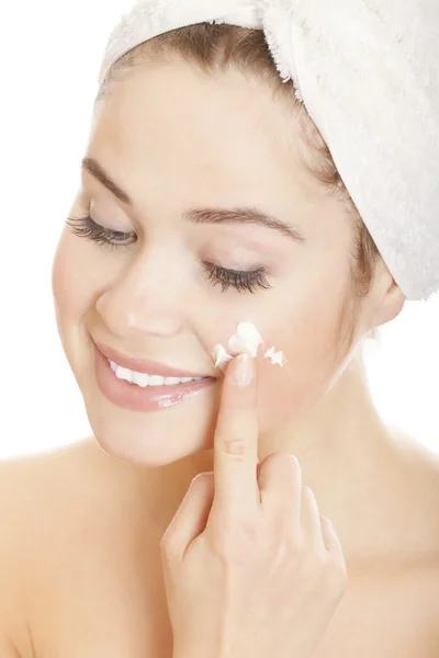 Beautiful smiling woman applying moisturizer cream on her face — Stok fotoğraf