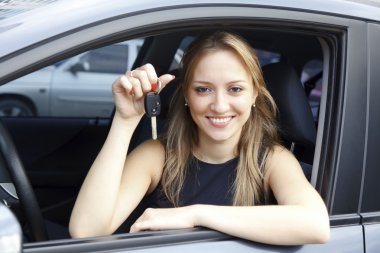 The happy woman showing the key of her new car. clipart