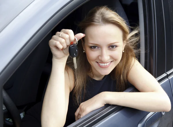 Счастливая женщина показывает ключ от своей новой машины — стоковое фото