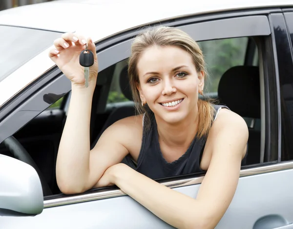 Belle jeune femme heureuse en voiture montrant les clés — Photo