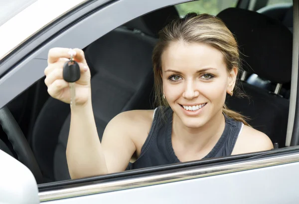 Beautiful young happy woman in car showing the keys — Stock Photo, Image