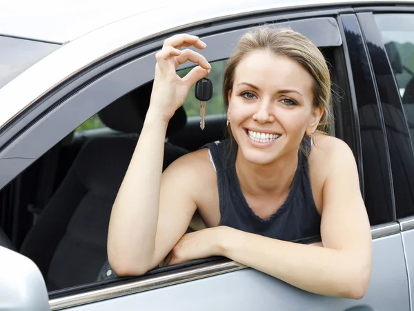 Bela jovem feliz mulher no carro mostrando as chaves — Fotografia de Stock