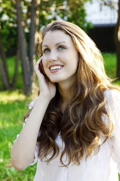 Młoda kobieta uśmiechający się mówi przez telefon komórkowy — Zdjęcie stockowe