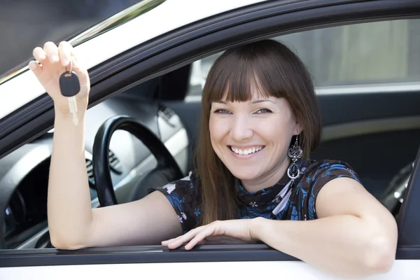 Chica bonita en un coche mostrando la llave — Foto de Stock