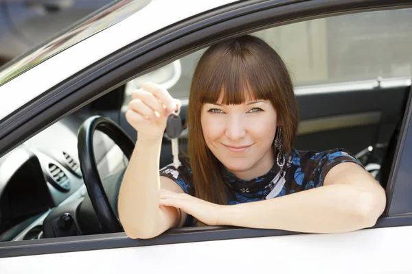 Pretty girl in a car showing the key. — Stock Photo, Image