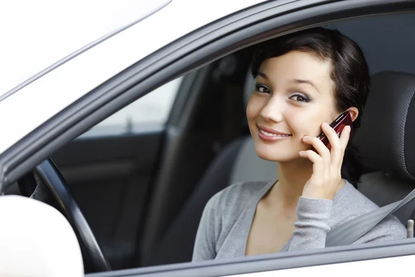 Щаслива молода жінка говорить по мобільному телефону, сидячи в машині — стокове фото