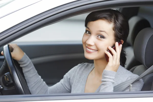 खुश युवा महिला सफेद कार में बैठे सेल फोन पर बात करती है — स्टॉक फ़ोटो, इमेज