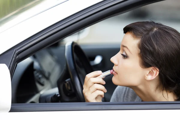Mujer bastante joven en un coche haciendo maquillaje — Foto de Stock